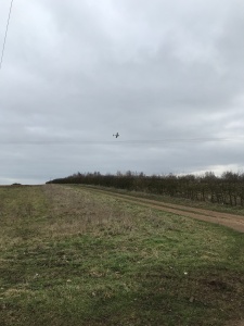 Grey sky over fields with small noisy plane flying overhead